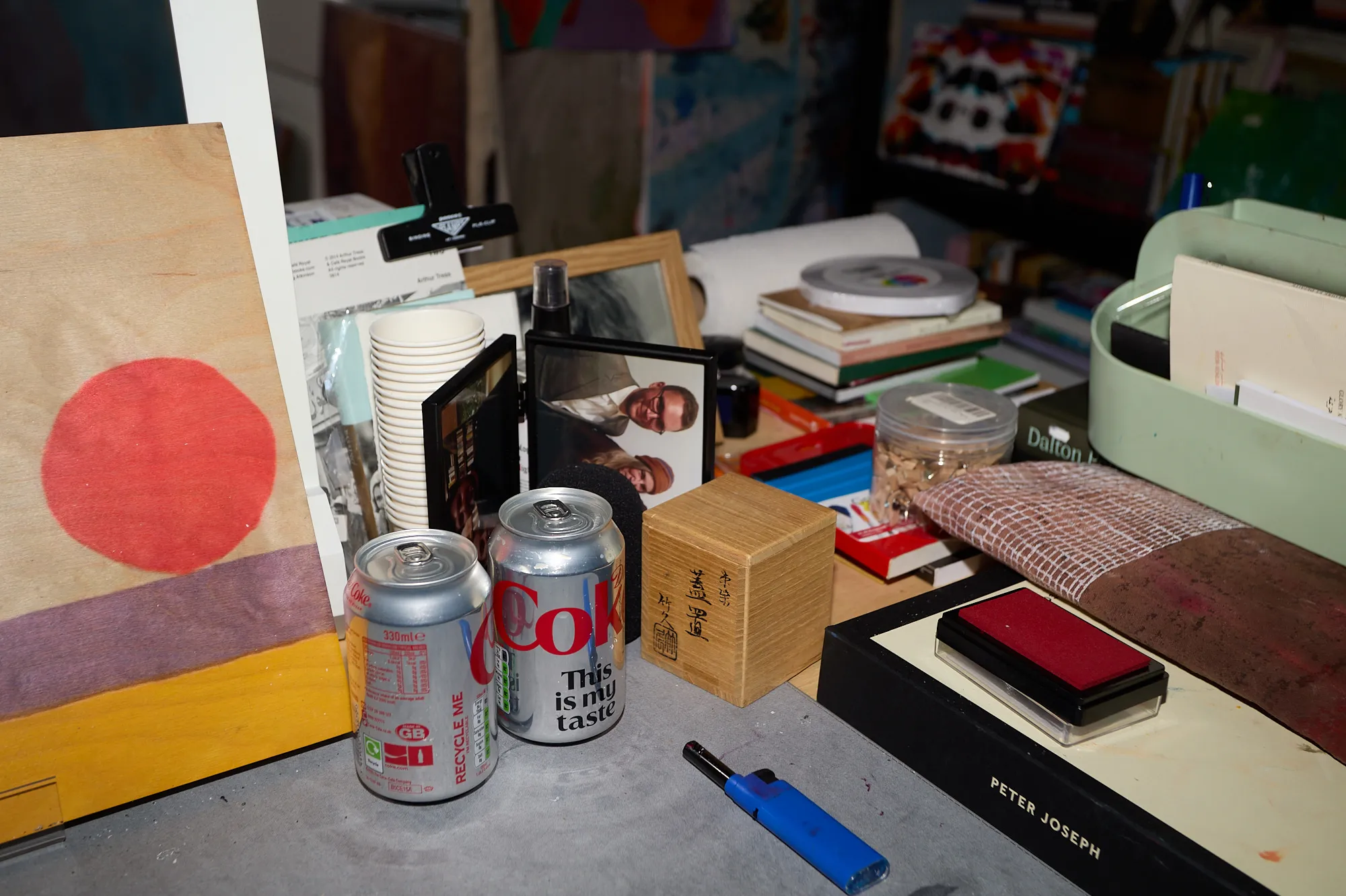 Coke cans, a stamp pad and framed photographs cluttering a desk in Omar Kholeif's studio