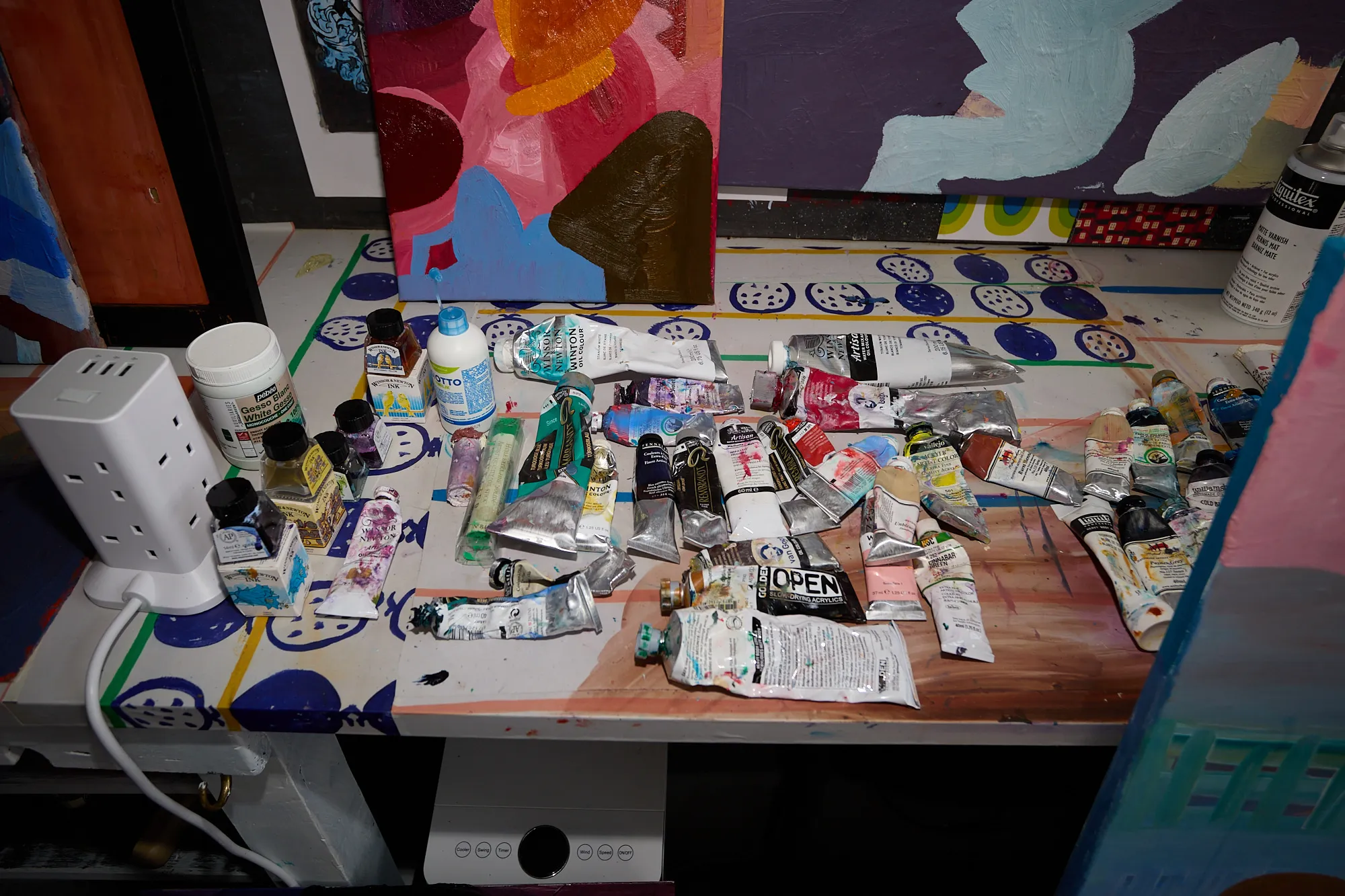 Dozens of paint tubes and ink bottles scattered across a desk in Omar Kholeif's studio