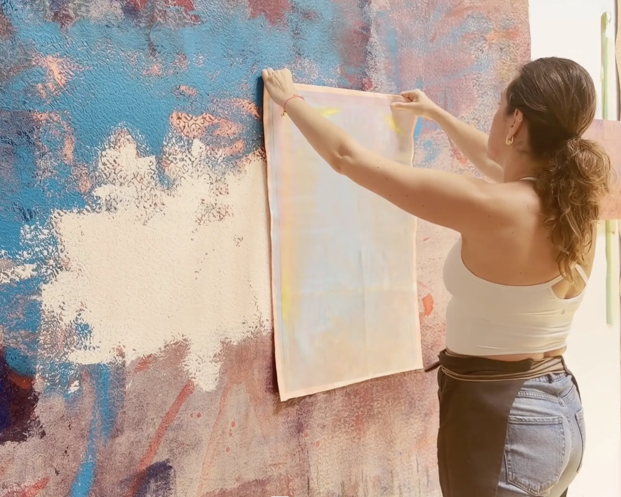 Chafa Ghaddar hanging a painted canvas panel on her studio wall