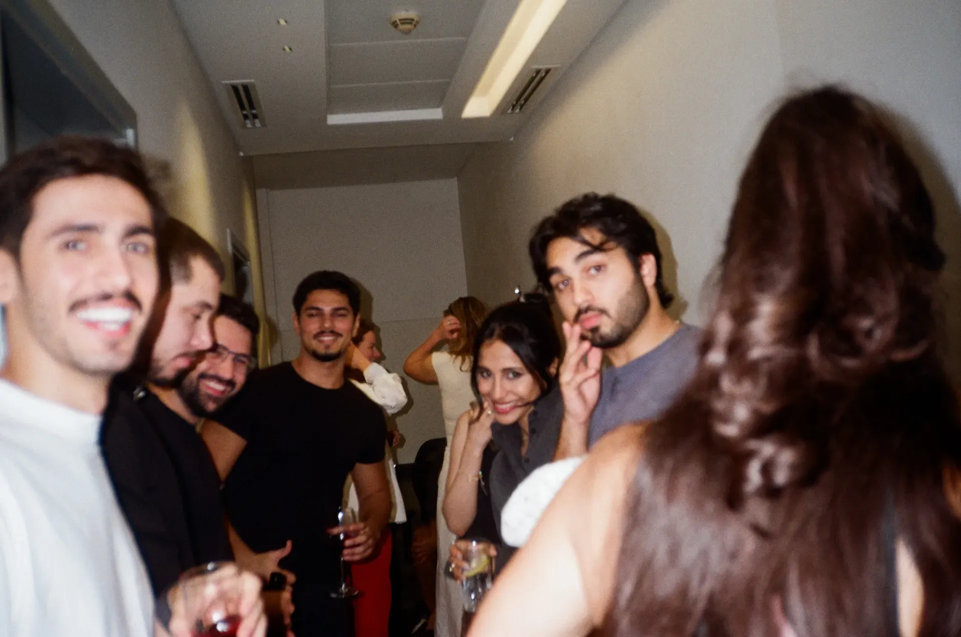 A group of guests smiling and holding drinks in a hallway